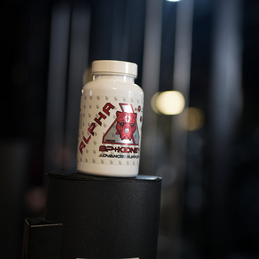 A white bottle of Alpha NeonAdvanced Support supplement with a red and black logo, displayed on top of a black stand in a dark gym environment.